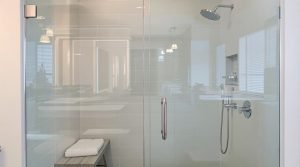 A sleek glass-enclosed shower in New Westminster, BC, featuring a rain showerhead, a built-in shower niche, and a modern bench for added comfort.